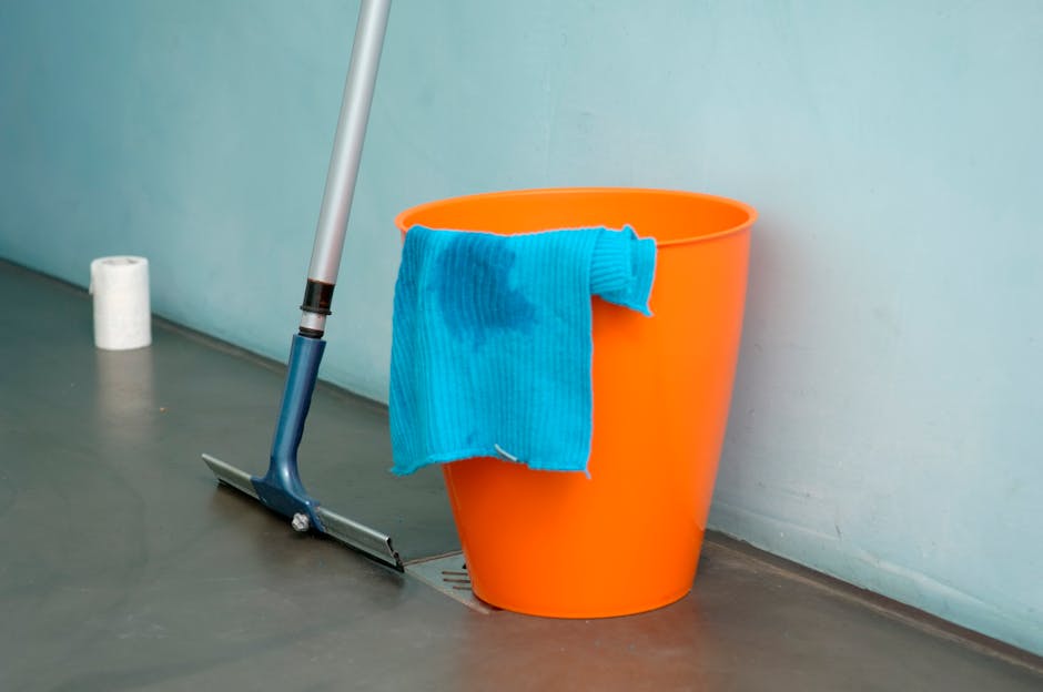 A person wearing brown rubber gloves is adjusting a lit sign with the words 'CLEANING HOME' in bold letters, placed on a flat surface indoors. The background shows a modern, softly lit room with a hint of a window, suggesting a clean and tidy environment. The sign is illuminated from within, emphasizing the message related to domestic surface cleaning and hygiene services. This image illustrates professional cleaning practices, aligning with the services offered by Carpet Cleaners Highbury to maintain hygienic and well-maintained homes.